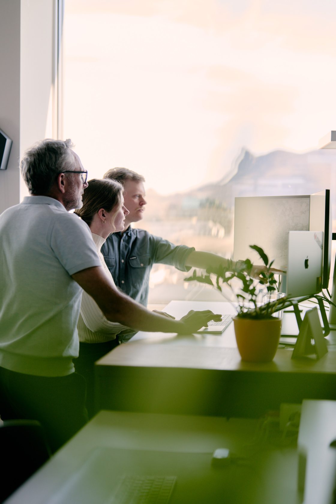 Spontaneous discussion of a feature – three employees standing around a desk and looking at the monitor.