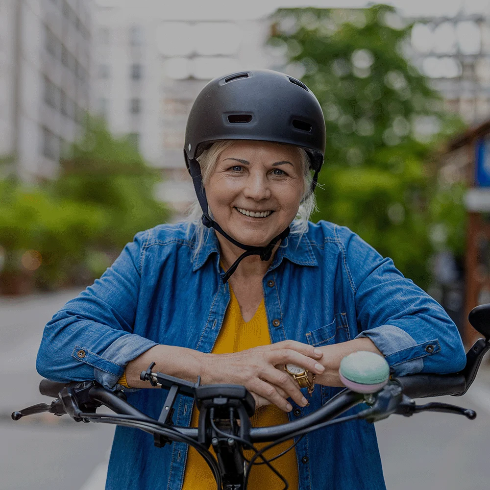 Lächelnde Frau mit Fahrradhelm auf ihrem Fahrrad.