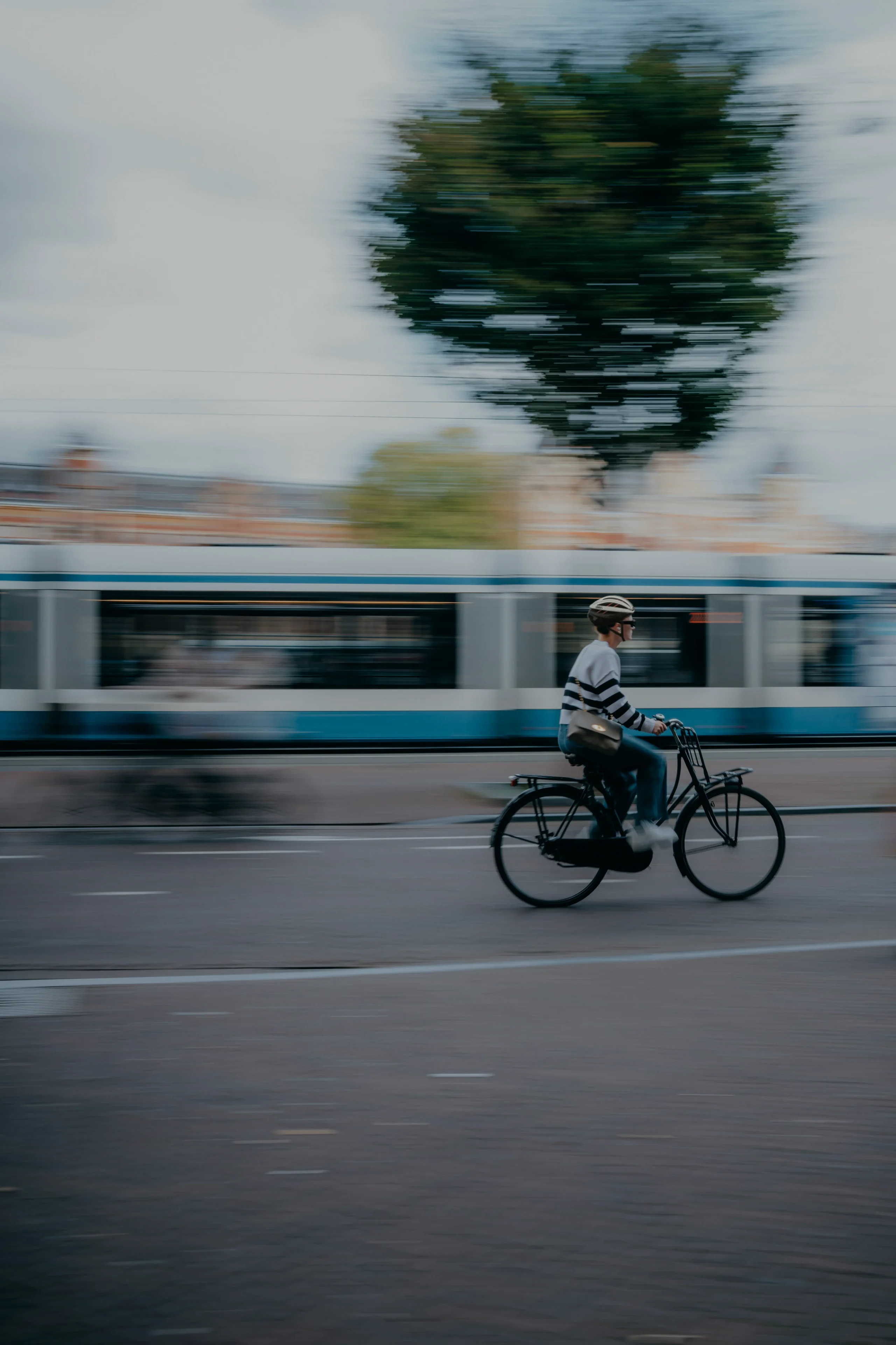 Frau fährt Fahrrad, im Hintergrund ist eine Straßenbahn zu sehen.